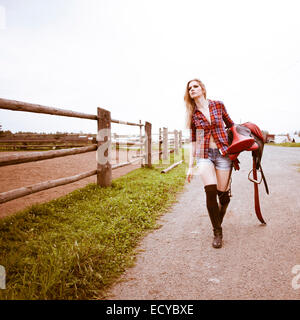 Portrait femme portant selle de cheval sur ranch Banque D'Images