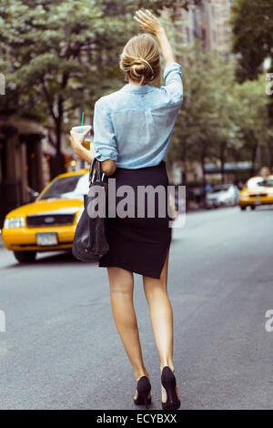 Caucasian woman hailing taxi dans la rue en milieu urbain Banque D'Images