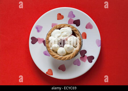 Tesco des fraises fraîches et crème Flan sur plaque coeur isolé sur fond rouge Banque D'Images