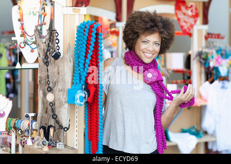 Mixed Race woman trying on colliers en magasin Banque D'Images