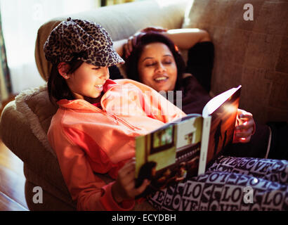 Mother and Daughter reading book on sofa Banque D'Images