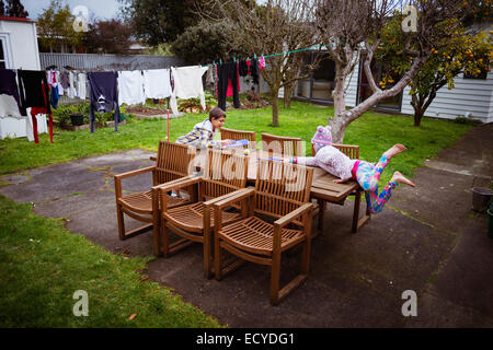 Mixed Race brother and sister playing at table in backyard Banque D'Images