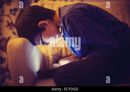 Mixed Race boy using digital tablet on sofa Banque D'Images