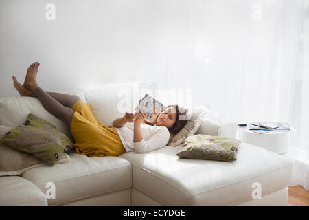 Mixed Race woman using digital tablet sur salon canapé Banque D'Images