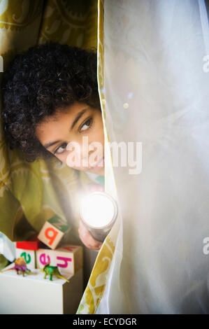 Mixed Race boy avec torche de peering fort générale Banque D'Images