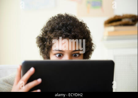 Mixed Race boy using digital tablet in living room Banque D'Images