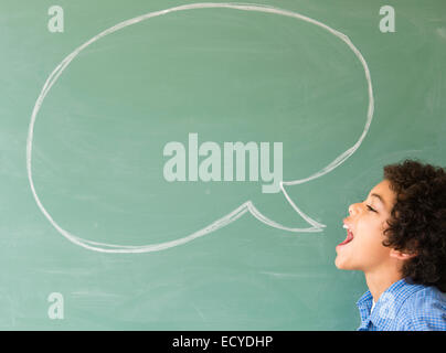 Mixed Race boy criant en speech bubble on chalkboard Banque D'Images