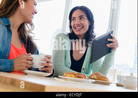 Les femmes hispaniques using digital tablet au petit déjeuner Banque D'Images