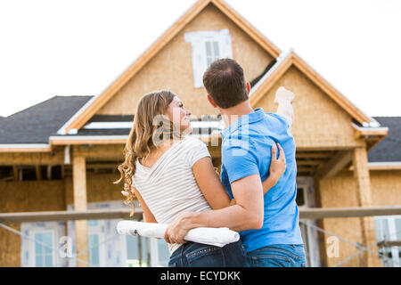 Caucasian couple admiring house under construction Banque D'Images