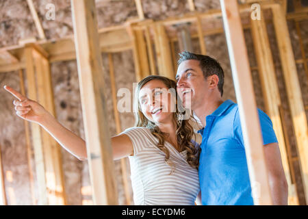 Caucasian couple admiring house under construction Banque D'Images