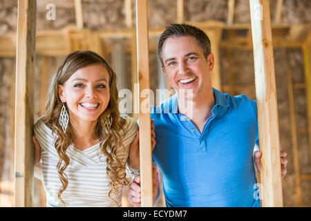 Caucasian couple smiling in house under construction Banque D'Images