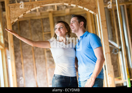 Caucasian couple admiring house under construction Banque D'Images