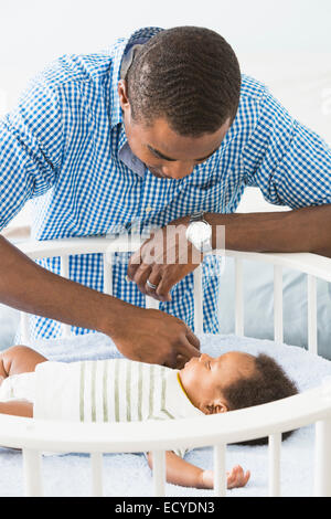 Père d'admirer bébé endormi dans son berceau Banque D'Images