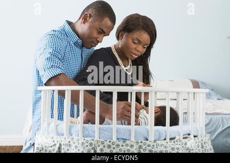 Couple admiring bébé endormi dans son berceau Banque D'Images