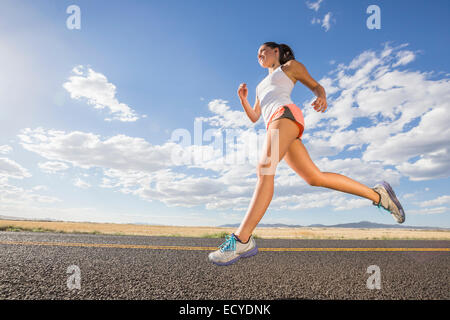 Low angle view of young woman running on remote road Banque D'Images