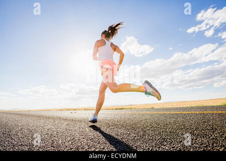 Low angle view of young woman running on remote road Banque D'Images