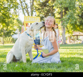 Pet dog licking face de Caucasian girl sur pelouse Banque D'Images