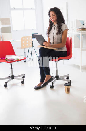 Mixed Race businesswoman using digital tablet in office Banque D'Images