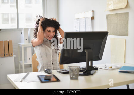 Mixed Race businesswoman frustré à computer at desk in office Banque D'Images