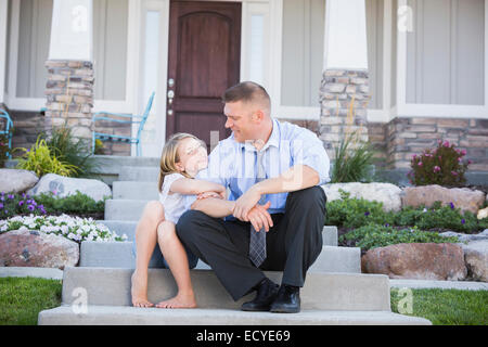 Caucasian father and daughter sitting on/stoop Banque D'Images