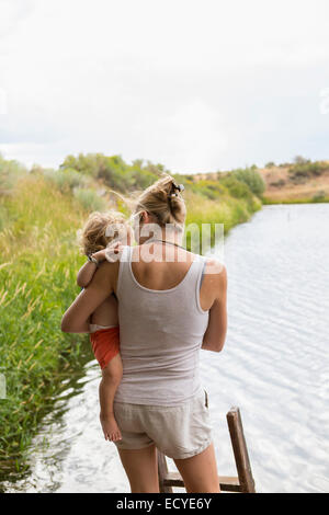 Caucasian mother holding baby son près du lac Banque D'Images