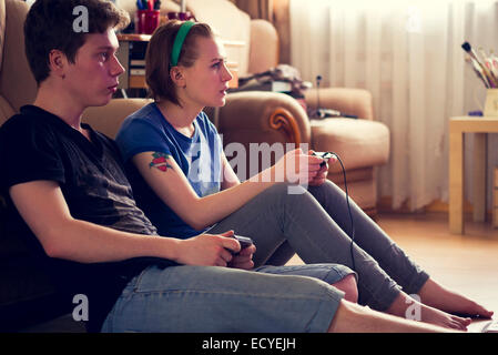 Couple playing video games sur plancher du salon Banque D'Images