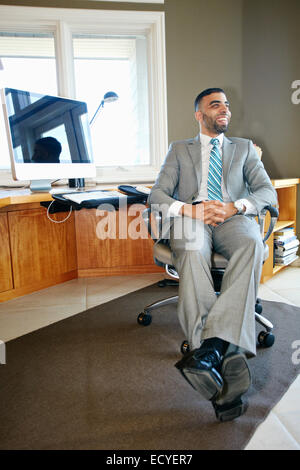 Middle Eastern woman relaxing in chair at desk in office Banque D'Images
