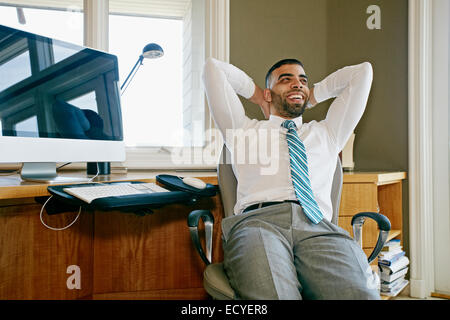 Middle Eastern woman relaxing in chair at desk in office Banque D'Images