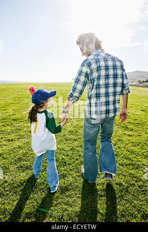 Père et fille walking in grassy field Banque D'Images