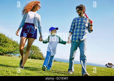 Les parents et la fille walking in grassy field Banque D'Images