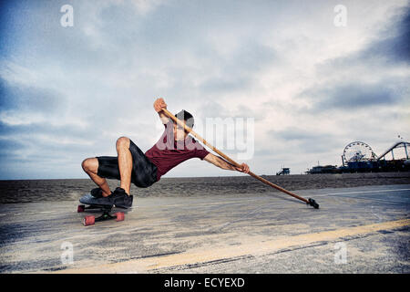 Caucasian man skateboarding avec palettes de pôle à beach Banque D'Images
