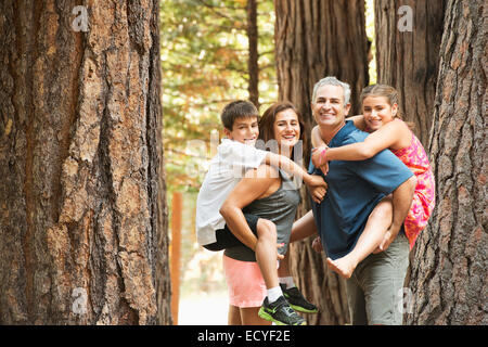 Les parents transportant des enfants s'y greffent en forêt Banque D'Images