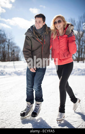 Caucasian couple patinage sur lac gelé Banque D'Images