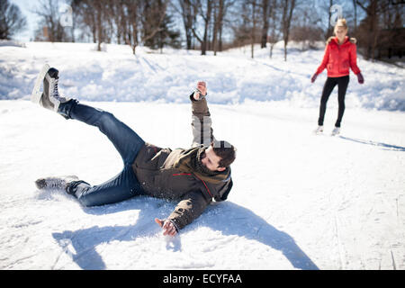 Caucasian man chute lors du patin à glace sur le lac gelé Banque D'Images