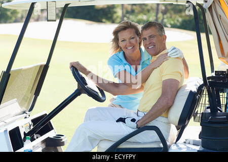 Caucasian couple hugging in golf cart on course Banque D'Images