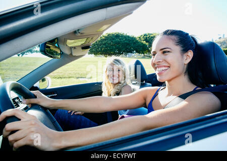 Les femmes excitées driving convertible on road trip Banque D'Images