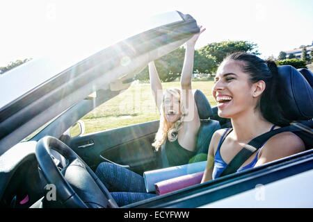 Les femmes excitées driving convertible on road trip Banque D'Images