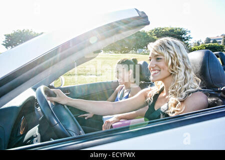 Les femmes excitées driving convertible on road trip Banque D'Images