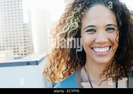 Mixed Race woman smiling on urban rooftop Banque D'Images