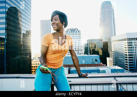 Black woman listening to écouteurs on urban rooftop Banque D'Images