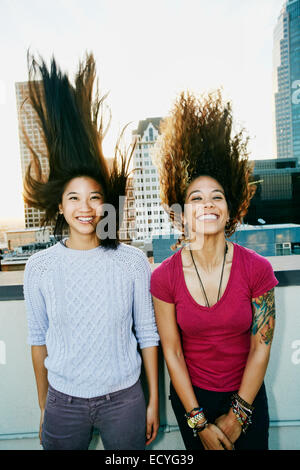 Les femmes jetant leurs cheveux on urban rooftop Banque D'Images