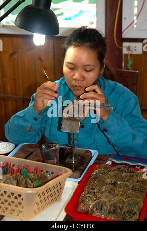 Travailleur sur une ferme perlière de placer du sable dans une coquille d'huître à cultiver une perle de culture, la baie d'Ha Long, Vietnam. Banque D'Images