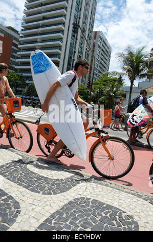RIO DE JANEIRO, Brésil - le 27 octobre 2013 : Man rides un vélo transportant de surf le long de la piste cyclable de la promenade à la plage d'Ipanema Banque D'Images