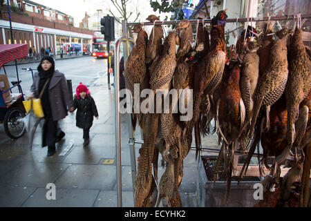 Faisans de raccrocher à l'extérieur d'un des bouchers traditionnels britanniques shop sur Bethnal Green Road, Londres, Royaume-Uni. Une fois qu'une zone britannique blanc, t Banque D'Images