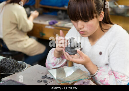 Femme au travail de l'usine de terre cuite sur une sculpture d'un bébé dragon dans Xi'an, Chine Banque D'Images