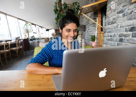 Young smiling woman en utilisant Apple MacBook ordinateur portable Banque D'Images