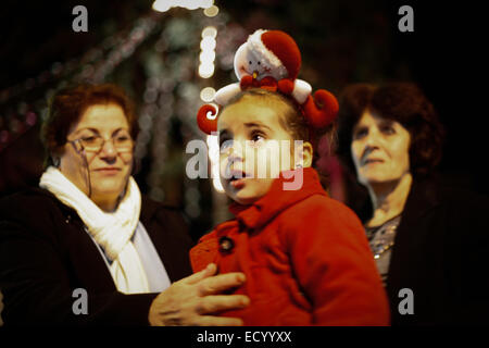 La bande de Gaza. Dec 22, 2014. Famille chrétienne palestinienne à Gaza s'allume à l'extérieur de l'Eid de l'arbre de Noël l'Église orthodoxe de la ville de Gaza. Credit : Ahmed Hjazy/Pacific Press/Alamy Live News Banque D'Images