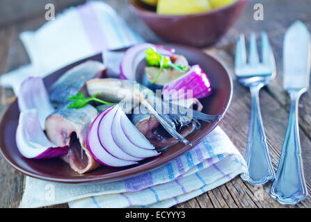 Le hareng à l'oignon dans un bol et sur une table Banque D'Images