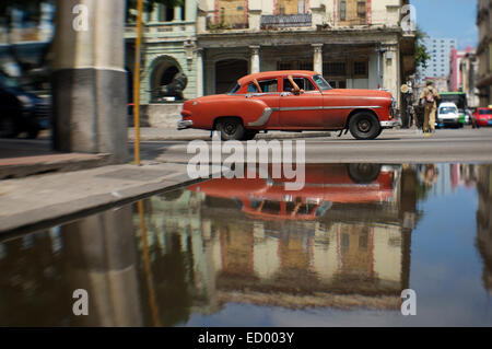 American Vintage rouge taxi voiture roulant sur La Havane Cuba street reflétant in puddle Banque D'Images