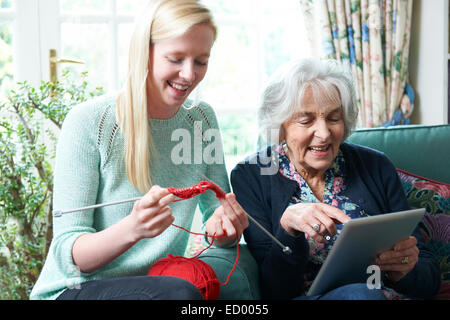 Grand-mère Using Digital Tablet tandis que sa petite-fille tricote Banque D'Images